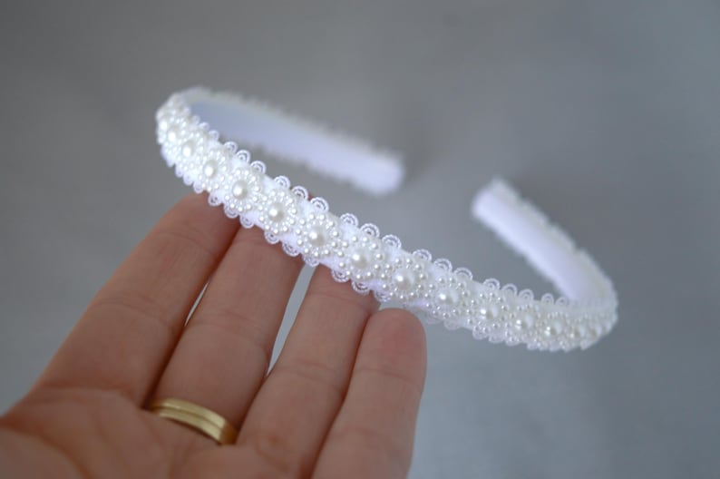 May include: White headband with a row of pearl-like embellishments.