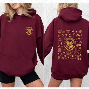 Puede incluir: Sudadera color burdeos con un escudo dorado de Hogwarts en la parte delantera y una variedad de iconos con temática de Hogwarts en la parte posterior. Los iconos incluyen el escudo de Hogwarts, el Sombrero Seleccionador, la Snitch Dorada y el símbolo de las Reliquias de la Muerte.