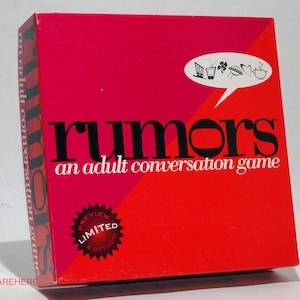May include: A red and pink box for the adult conversation game "Rumors." The box features the game's title in large black letters, with the tagline "an adult conversation game." A white speech bubble with small illustrations is in the upper right corner.
