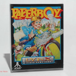 May include: Paperboy Atari Lynx video game card. The box art features a cartoon paperboy riding a bicycle, delivering newspapers. The Paperboy title is in yellow and red. The Atari Lynx logo is visible.