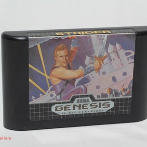 May include: Black Sega Genesis 16-bit cartridge for the game Strider. The label features a muscular man with a sword, set against a futuristic backdrop. The Sega Genesis logo is prominently displayed.