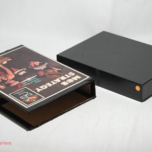 May include: A black box with a game board inside. The game board is titled "Mob Strategy" and features a colorful illustration of people playing a game. The box is open and the game board is visible.