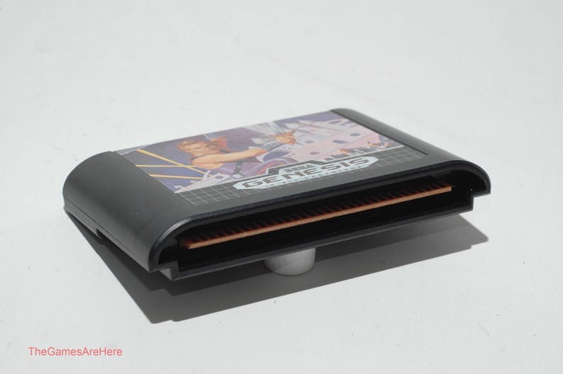 May include: A black Sega Genesis video game cartridge. The cartridge has a colorful label with a graphic of a person and the Sega Genesis logo. The cartridge is resting on a small, silver stand.