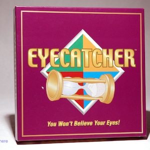 May include: A purple box with a gold hourglass design and the text "EYECATCHER" in gold letters. The box also has the text "You Won't Believe Your Eyes!" in white letters.