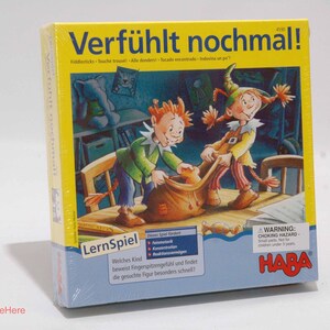 May include: A yellow, blue, and red board game box with the title "Verfühlt nochmal!" and the HABA logo. The box features illustrations of two children playing a game.