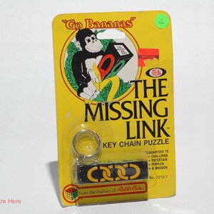 May include: A vintage The Missing Link key chain puzzle in its original yellow blister pack packaging. The card features a cartoon gorilla, the text Go Bananas, and the Ideal logo. The puzzle is a black rectangular bar with yellow chain links.