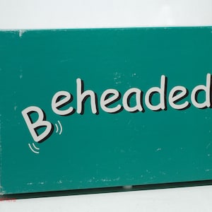May include: A teal blue box with the word "Beheaded" printed in white on the front.