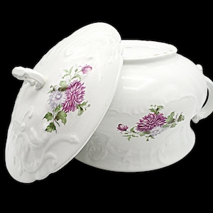 May include: White porcelain soup tureen with a lid, featuring a floral design with pink and white flowers. The tureen has two handles and a decorative embossed design.