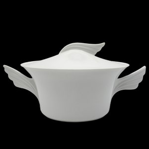 May include: White porcelain serving dish with a lid and two wing-shaped handles. The dish is round and has a smooth, glossy finish.