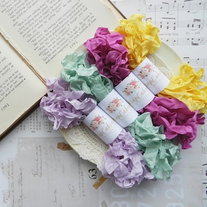 May include: Five spools of colorful, crinkled ribbon with a floral design and the text "Wrap Cabin" on each spool.