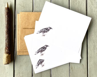 May include: A set of three blank white note cards with a black and white illustration of a bird on each card. The cards are stacked on top of each other.