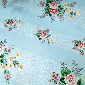 May include: Light blue floral fabric with white lace-like stripes. The fabric features clusters of pink, red, and yellow flowers with green leaves. The pattern is repeated across the fabric.