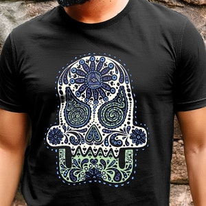 May include: A black t-shirt with a white sugar skull design. The skull is decorated with blue and green floral patterns. The skull has a third eye in the center of its forehead.