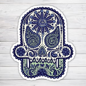 May include: A white sugar skull sticker with blue and green paisley patterns. The skull has an all-seeing eye in the forehead.