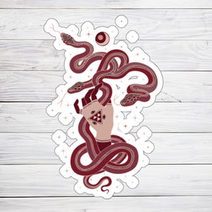 Peut inclure: Un autocollant représentant une main avec un troisième œil et un symbole triangulaire, entourée de trois serpents rouges avec des points blancs. L'arrière-plan est blanc avec de petites étoiles blanches.