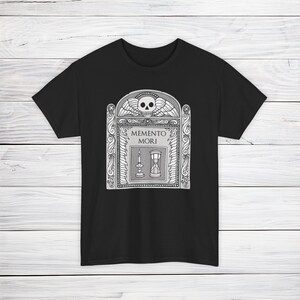 Illustration of a grave stone from the 1800s with a skull, candle, and hourglass on it. States Memento Mori. Design on a t-shirt.
