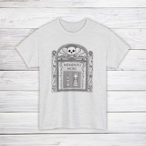 Illustration of a grave stone from the 1800s with a skull, candle, and hourglass on it. States Memento Mori. Design on a t-shirt.