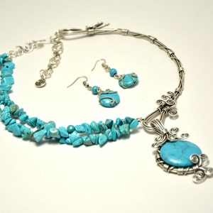 May include: A turquoise gemstone necklace and earrings set with a silver wire wrapped pendant and a silver chain. The necklace has three strands of turquoise chips.