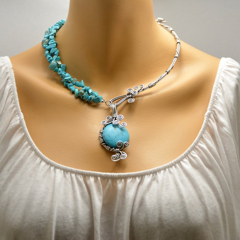 May include: A silver wire necklace with a turquoise stone pendant and a turquoise stone strand. The necklace is on a mannequin.