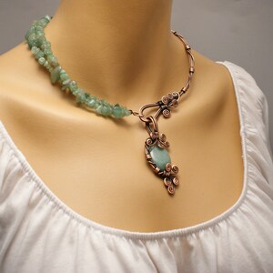 Peut inclure: Un collier en fil de cuivre avec un pendentif en pierre verte. Le collier est compos&eacute; de deux brins de fil de cuivre, dont l'un est enroul&eacute; autour d'une pierre verte. Le pendentif est une grande pierre verte de forme ovale sertie dans un cadre en fil de cuivre. Le collier est un bijou magnifique et unique.