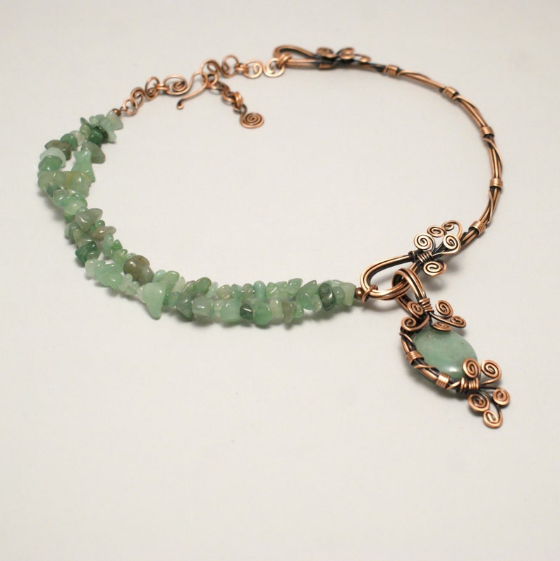 Peut inclure: Un collier en fil de cuivre avec un pendentif en pierre verte et un double rang de perles en pierre verte.