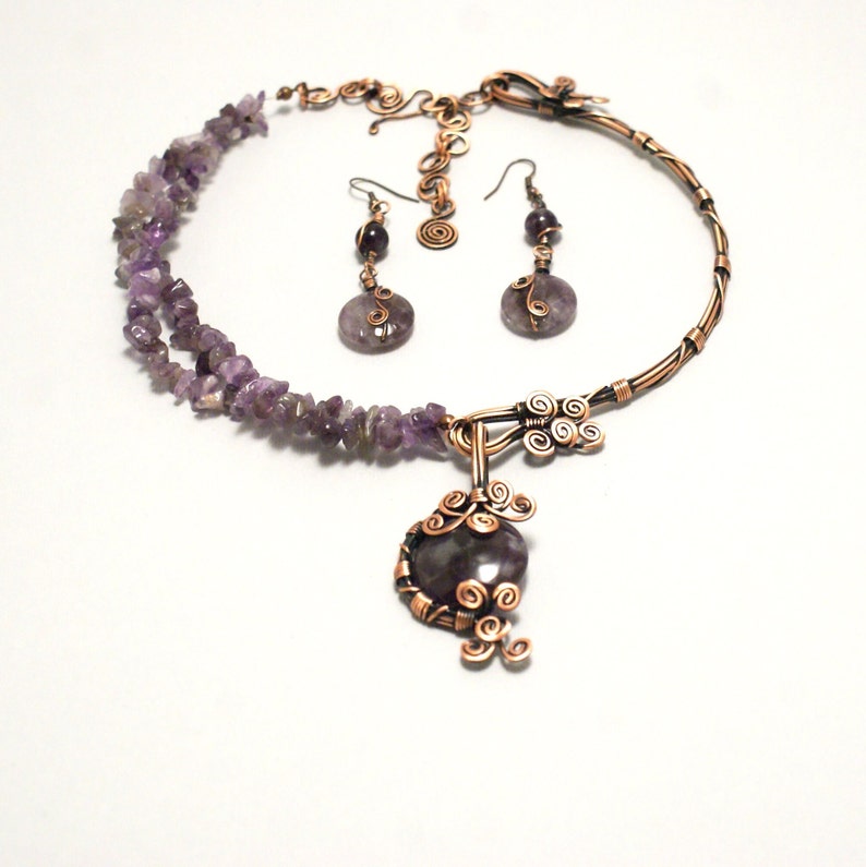 May include: A copper wire necklace with amethyst stones and a pendant. The necklace is paired with matching earrings.