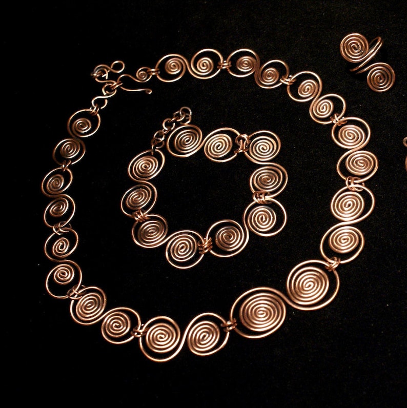 May include: A set of copper wire jewelry featuring a necklace, bracelet, and ring. Each piece is made of interconnected spiral shapes.