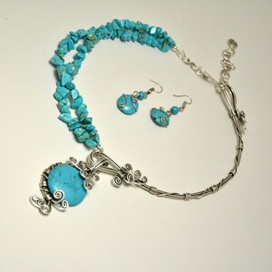 May include: A turquoise and silver necklace and earrings set. The necklace features a large turquoise stone pendant with silver wire detailing. The earrings are silver with turquoise stones.