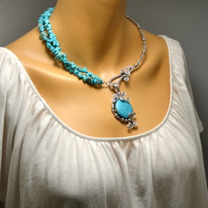 May include: A turquoise stone necklace with a silver wire design. The necklace features a large turquoise stone pendant and a double strand of turquoise chips.
