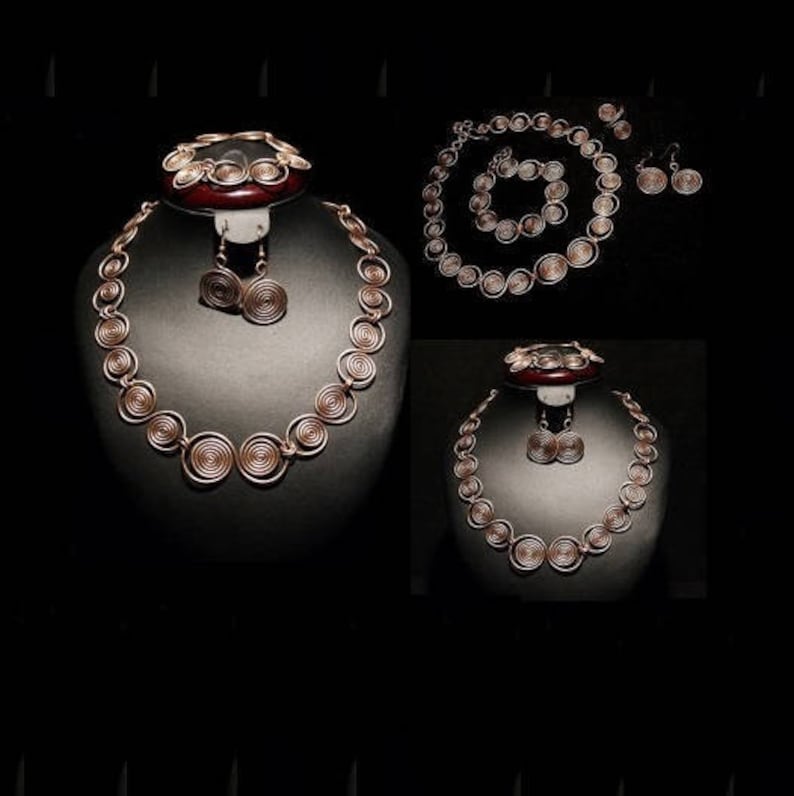 May include: A set of three gold-toned jewelry pieces: a necklace, a bracelet, and a pair of earrings. The jewelry is made of coiled wire, creating a circular pattern.