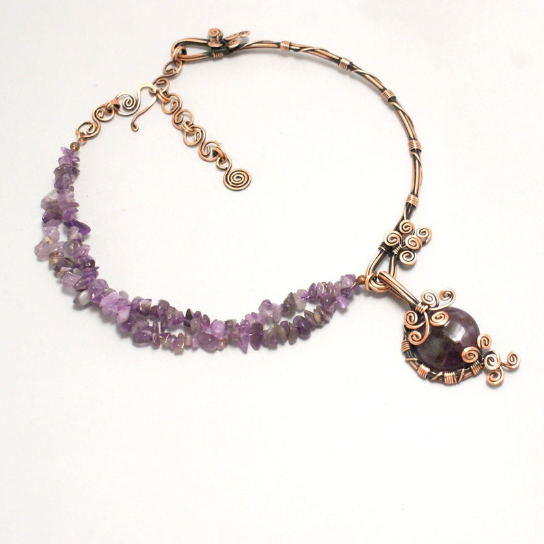 May include: A copper wire necklace with a large amethyst pendant. The pendant is surrounded by copper wire swirls and the necklace is made with a double strand of small amethyst chips.