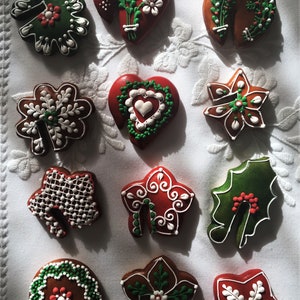 May include: Twelve gingerbread cookies decorated with white and green icing. The cookies are in the shapes of hearts, stars, leaves, and bells.