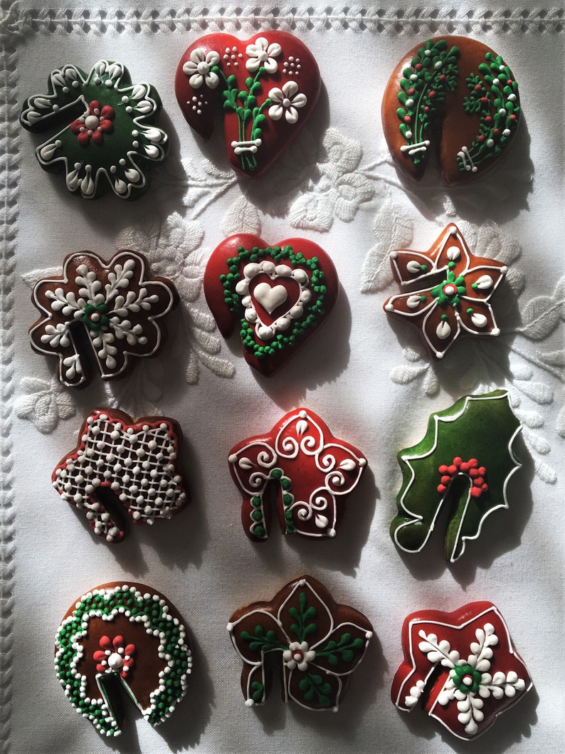 May include: Twelve gingerbread cookies decorated with white and green icing. The cookies are in the shapes of hearts, stars, leaves, and bells.