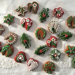 May include: Assortment of Christmas-themed gingerbread cookies decorated with white and green icing. The cookies are shaped like hearts, stars, leaves, and holly.