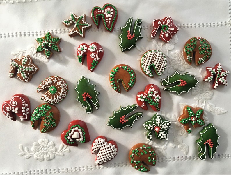 May include: Assortment of Christmas-themed gingerbread cookies decorated with white and green icing. The cookies are shaped like hearts, stars, leaves, and holly.