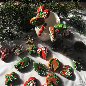 May include: An assortment of Christmas cookies decorated with green and white icing. The cookies are shaped like hearts, stars, leaves, and flowers. Some of the cookies are arranged in a white mug.