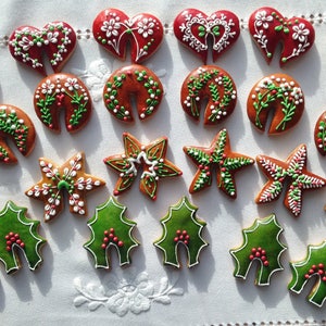 May include: Assortment of Christmas cookies decorated with red, green and white icing. The cookies are shaped like hearts, stars, holly leaves and wreaths.