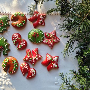 May include: Assortment of Christmas cookies decorated with green and red icing. The cookies are shaped like holly leaves, stars, and hearts.