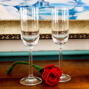 May include: A white ceramic mug with a black handle and the text "But First, Coffee" in a black, bold font. The mug is on a white surface.