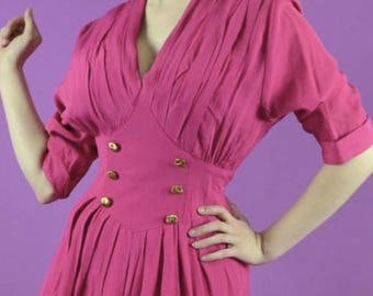 May include: A vibrant magenta midi dress featuring a V-neckline, elbow-length sleeves with cuffs, and a fitted bodice with six gold-toned buttons arranged in two vertical rows. The skirt is pleated at the waist, creating a full, flowing silhouette.
