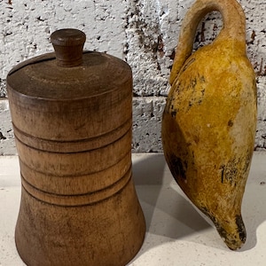 May include: A wooden container with a lid and a yellow ceramic pitcher with a handle. The container has a grooved design and the pitcher has a textured surface.