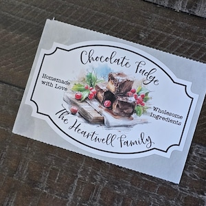 May include: A label for chocolate fudge on a white background. The label features the text "Chocolate Fudge", "Homemade with Love", "Wholesome Ingredients", and "The Heartwell Family". The label has an illustration of fudge with berries.