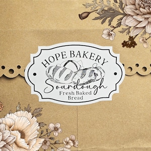May include: White sticker with black text that reads "Hope Bakery Sourdough Fresh Baked Bread". The sticker features a black and white illustration of three loaves of bread.