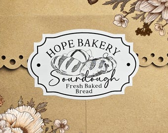 May include: White sticker with black text that reads "Hope Bakery Sourdough Fresh Baked Bread". The sticker features a black and white illustration of three loaves of bread.