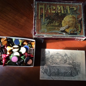 Puede incluir: Una caja de juego vintage para el juego "Palomar" publicado por E.I. Horsman en Nueva York. La caja es roja y presenta una ilustración colorida de una mujer con un escudo y una espada. La caja de juego está abierta y se puede ver una bandeja de piezas de juego coloridas.
