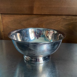 Puede incluir: Un tazón de plata con una base redondeada y una superficie lisa y reflectante.