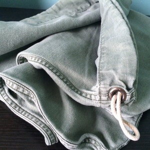 May include: A green canvas drawstring bag with a white cord and a metal ring.