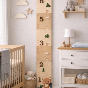 May include: A vertical wooden growth chart featuring puzzle-piece segments, numbered one through six. The top displays the name Isaiah above a mountain and forest scene. The design includes small wooden cutouts of trees, clouds, and a bear.