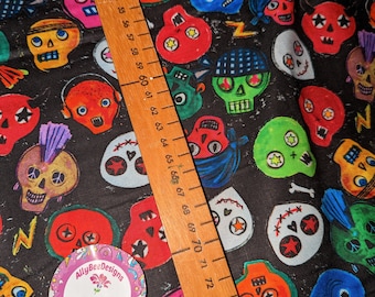 May include: Black fabric with a repeating pattern of colorful cartoon skulls. The skulls have different facial expressions and details, including bandanas, sunglasses, and mohawks. A wooden ruler is visible in the image, with markings from 46 to 77.