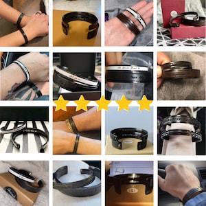 May include: A collection of black and silver engraved cuff bracelets with various inscriptions, including "I love you", "John 3:16", "John 13:34", "Colossians 2:21", "Colossians 2:24", "All Wonder Woman", "Superman", "A Million of the Love", "Until Death Do Us Part", "Thank You", and "Let go and be free".